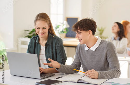 Wallpaper Mural Happy high school students using laptop computer in class. Smiling teenage student boy and girl sitting at desk in classroom and using laptop together. Education technology concept Torontodigital.ca