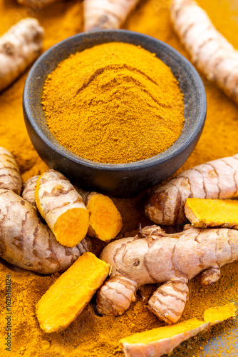 Fresh and Ground Turmeric Root on Rustic Background