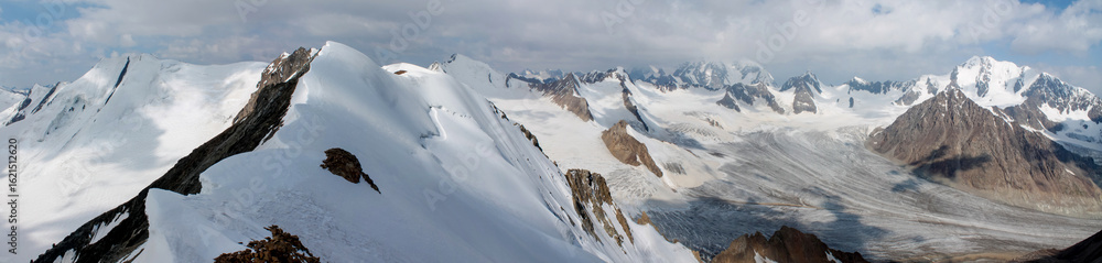 Fototapeta premium Panorama landscape of high altitude snow mountains of Tian Shan on border of Kyrgyzstan and China. Snow covered summits and valleys with huge glaciers Asia Tian-Shan mountain range extreme expedition