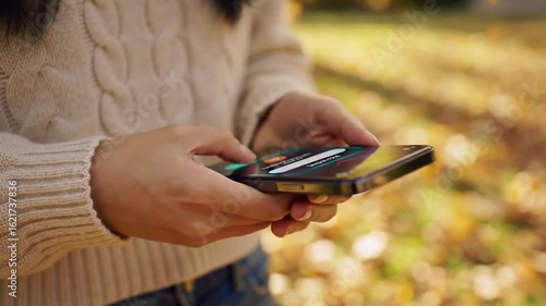 A young mother's hand is holding a smartphone to monitor her child with Parental Control technology on the smartphone.