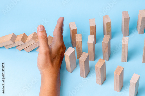 Canvas Print A Hand Stops A Row Of Falling Dominoes, Preventing Further Collapse And Chaos