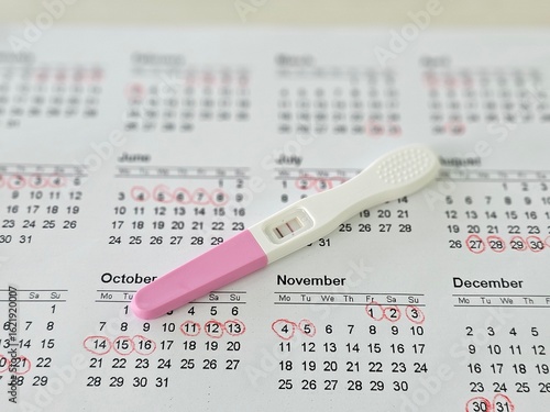 Fotografie Pregnancy test kit placed on marked calendar highlighting ovulation or menstrual