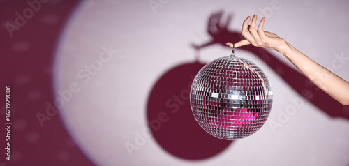 Obraz na plátne Female hand with disco ball on color background