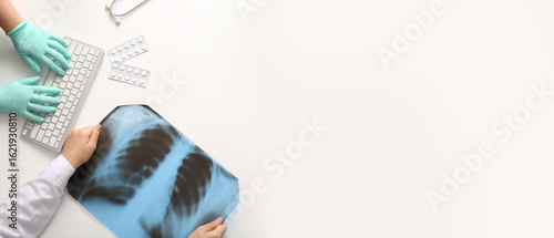 Doctor's hands with computer keyboard and x-ray on white background