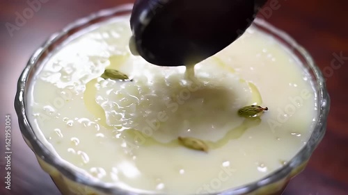 Delicious Kheer in Transparent Glass Bowl Garnished with Cardamom Pods and Ghee on Wooden Table Perfect for Festive Meals and Bakery Promotions with Creamy Texture Glistening in Sweetness