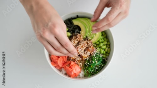 Hands Preparing Colorful Poke Bowl with Avocado, Edamame, and Ginger