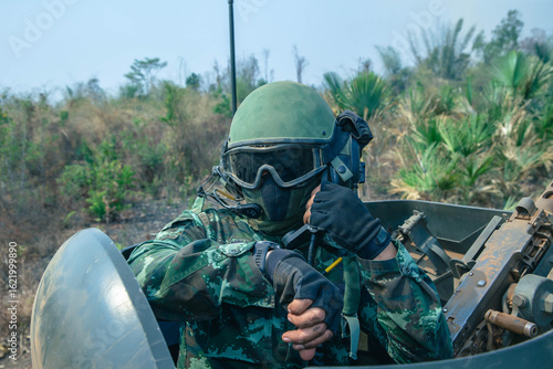 Soldier Using Communication Device, A soldier in full combat gear communicates via radio while riding inside an armored vehicle during a mission.