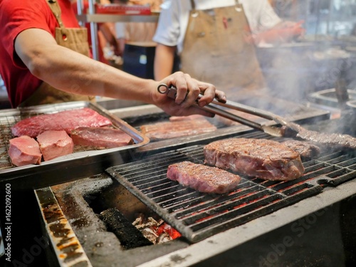 Grilling fresh steaks over open flame at a fine steak restaurant in Bangkok, Thailand, showcasing expert preparation and premium dining atmosphere.