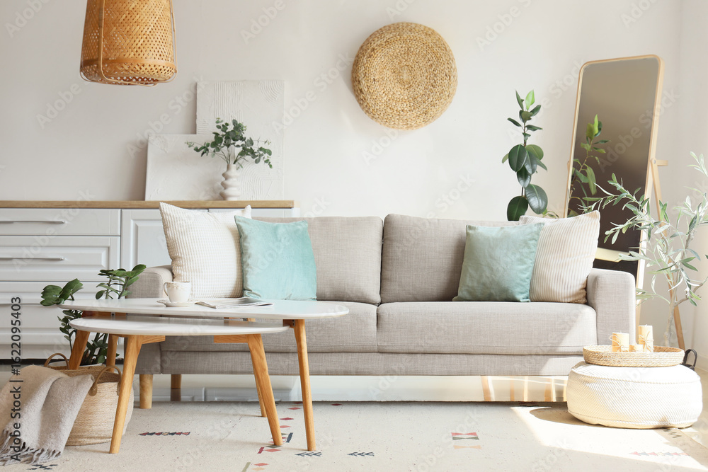 Obraz premium Interior of living room with comfortable sofa, pouf and tables near white wall