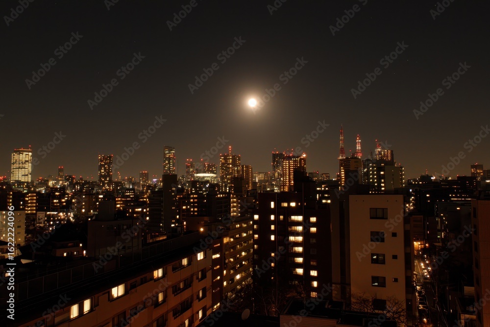 Fototapeta premium Illuminated cityscape at night with a bright full moon shining in a dark sky