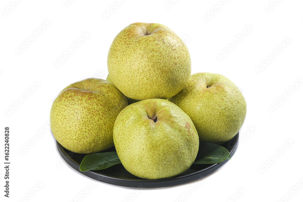 Fototapeta premium Display of Dangshan Crisp Pears on a black plate with fresh leaves against a white background