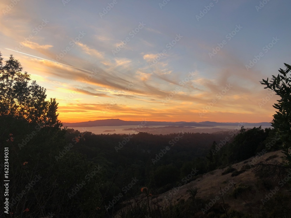 Obraz premium Golden Sunset Over Rolling Hills and Bay View