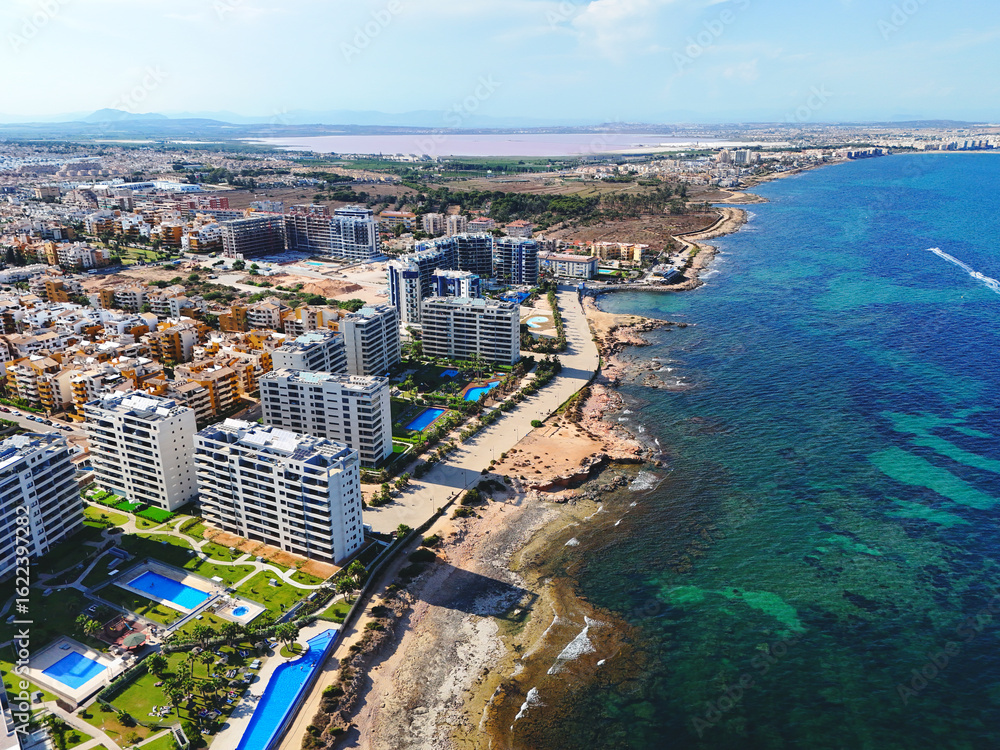 Obraz premium Aerial view of Punta Prima coastline with modern high-rise residential building. Costa Blanca, Alicante province. Spain