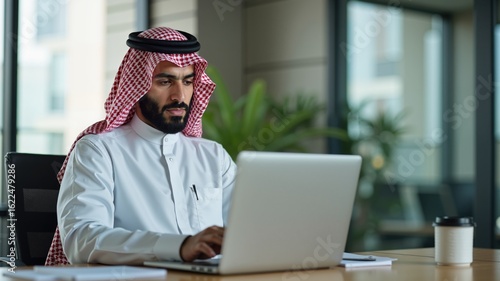 Arab Saudi man in office working in business corporate background using laptop or phone in a meeting.
