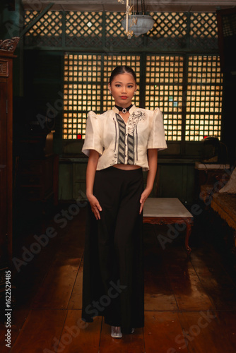 Slika na platnu Full-body portrait of Filipina woman in stylish Filipiniana attire standing confidently in a preserved Filipino ancestral home