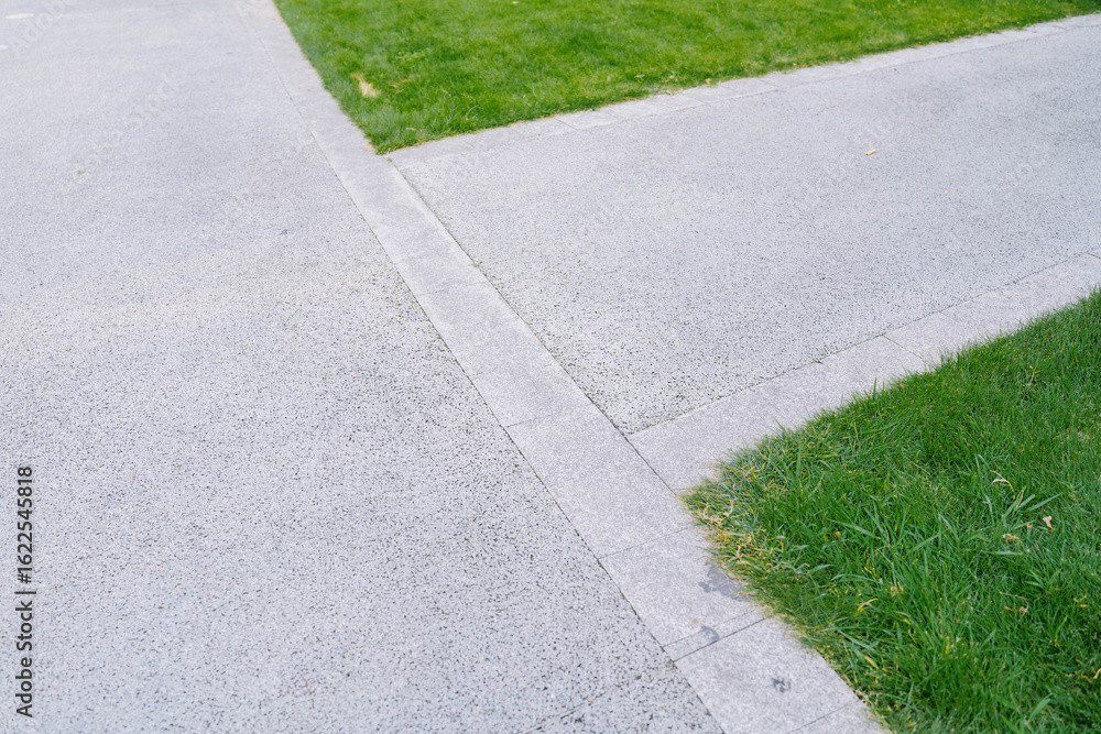 Obraz premium roadside of an concrete road with a stone curb in the background lawn with green grass