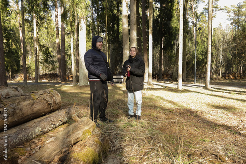 Wallpaper Mural Two people dressed in winter jackets standing in the woods, pausing for a warm drink from a thermos, enjoying nature, quiet conversation, and seasonal coziness. Torontodigital.ca