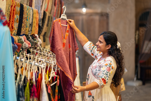 young Asian woman street shopping in Mumbai, she is looking at beautiful kaftan style dresses on Fashion street