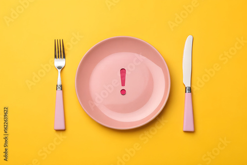 Pink Plate with Exclamation Mark and Cutlery on Yellow Background  
