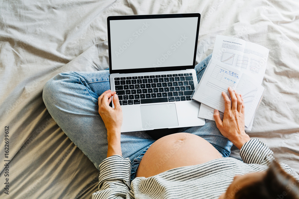 Naklejka premium Pregnant woman using laptop at home. Pregnant belly of expectant mother with computer.