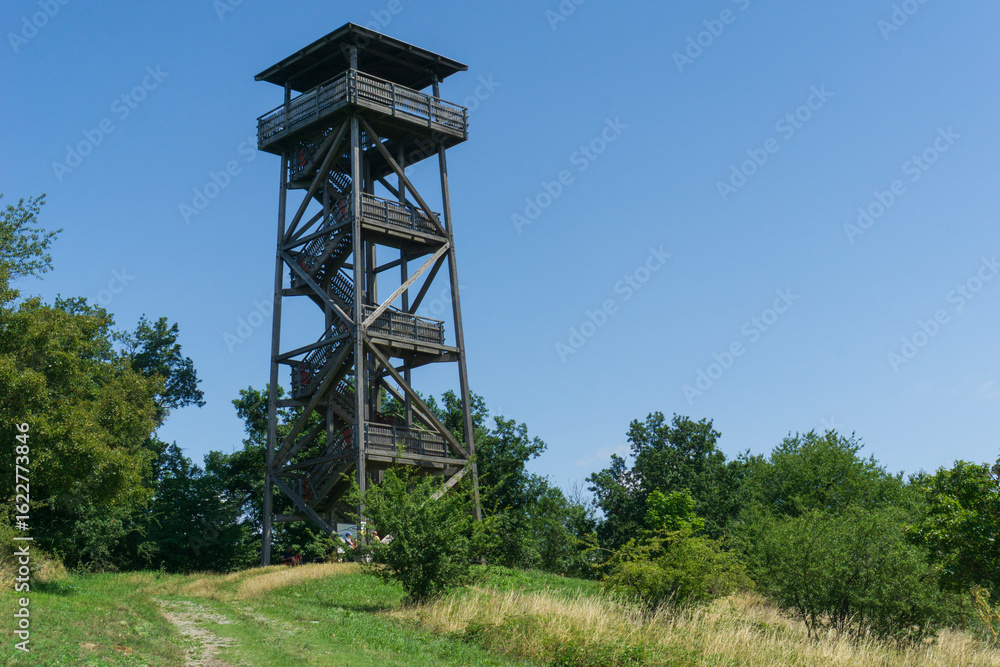 Tall wooden observation tower on a grassy hill under a clear blue sky, concept of hiking, lookout point, nature travel, viewpoint. Tall wooden observation tower on a grassy hill under a clear blue sky, concept of hiking, lookout point, nature travel, viewpoint.