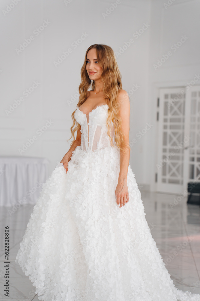 A bride with long blonde hair in a classic wedding dress in the living room. A bride with long blonde hair in a classic wedding dress in the living room.