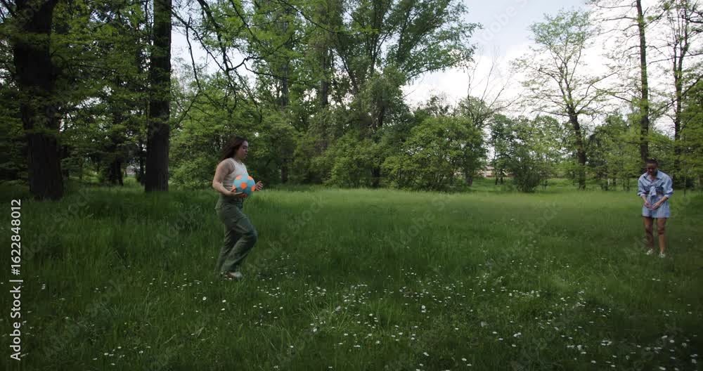 Two Friends Enjoy a Sunny Day Playing Volleyball in a Lush Park Filled with Wildflowers and Trees Two Friends Enjoy a Sunny Day Playing Volleyball in a Lush Park Filled with Wildflowers and Trees