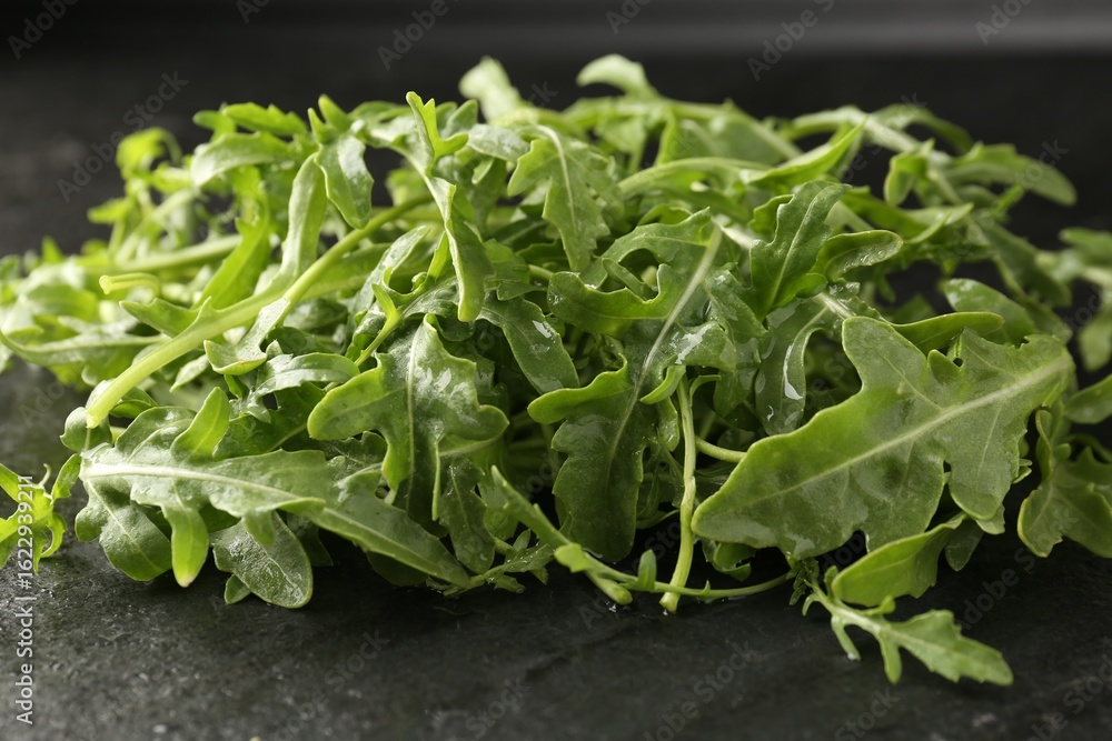 Fresh ripe green arugula leaves on black table, closeup Fresh ripe green arugula leaves on black table, closeup
