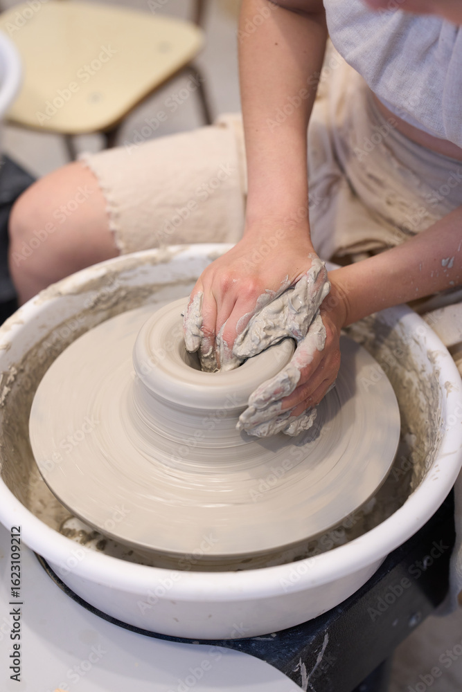 Fototapeta premium Potter creating ceramic vessel on pottery wheel in workshop