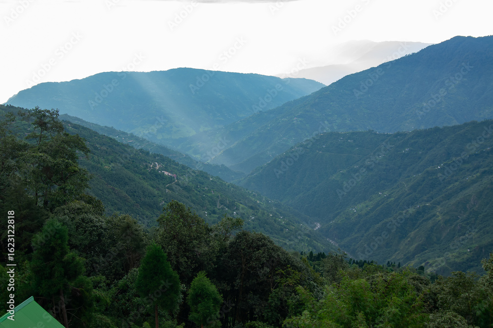 Naklejka premium Sun rays falling on Himalayan mountain range, scenic beauty of layers of mountains, Okhrey, sikkim, India. Okhrey village a remote place in Sikkim where mountain range view is enjoyed by tourists.
