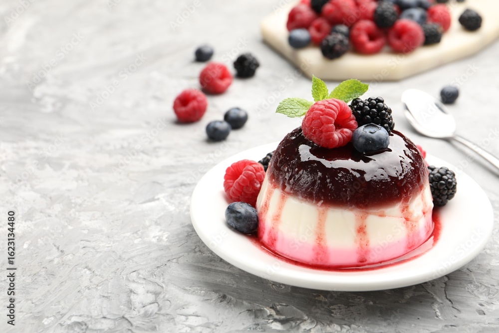 Naklejka premium Tasty panna cotta with berries and jam on light grey table, closeup. Space for text