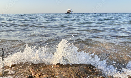 Waves Crashing on a Rocky Shore with a Boat on the Horizon