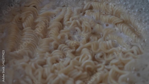 Cooking instant curly noodles in boiling water. Perfect for food blogs, cooking tutorials, and restaurant menus.