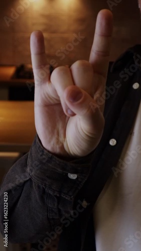 Man showing rock hand gesture symbolizing love for heavy metal music style. Punk rock