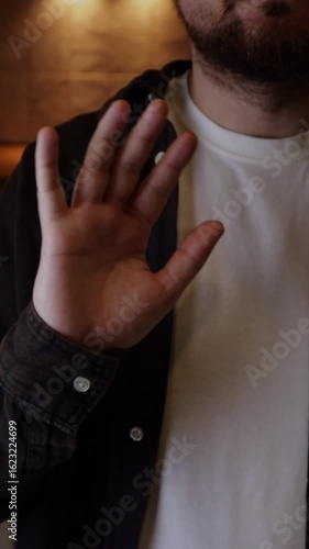 Man waving and greeting with hand as he notices someone. Person saying hello with hand