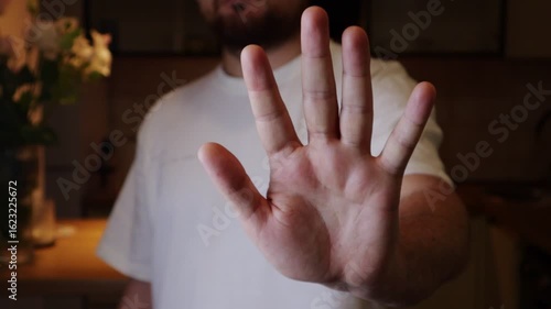 Person raising hand in a gesture of stop or warning. Person holding 5 fingers with open palm to the camera