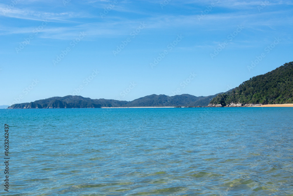 Fototapeta premium Serene Beach with Turquoise Waters and Distant Mountains