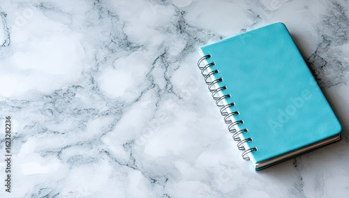 Light teal notebook on white marble surface