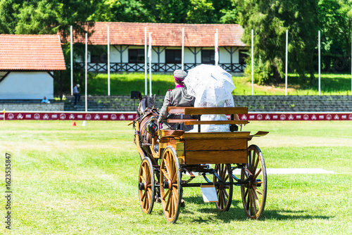 Obraz na płótnie Horse-drawn carriage with coachman and passengers dressed in elegant interwar-era style outfits
