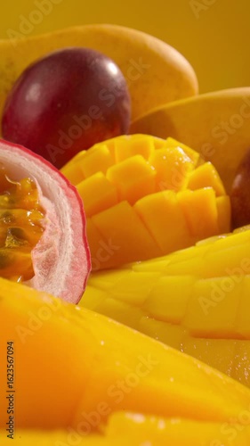 Tropical fruits juicy sliced mango passion fruit on yellow background. Summer fruit healthy food. Vertical shot