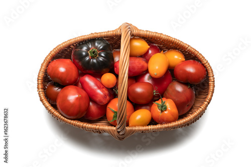 Wicker basket filled with colorful fresh tomatoes on a white background. A variety of tomato types including red, yellow, orange.