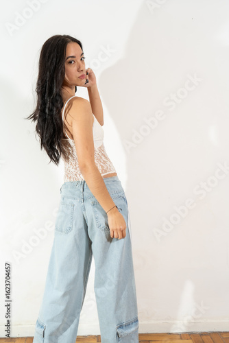 Young latin woman posing with white top and jeans, expressing confidence and style