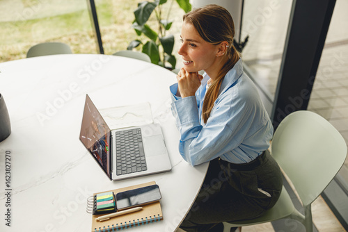 Canvas Print A dedicated and focused woman diligently working on her laptop amidst stationery