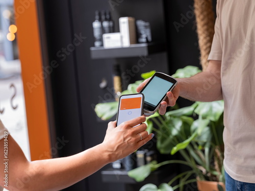 Close-up of contactless payment transaction between smartphone and payment card in contemporary environment