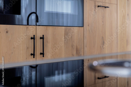 Tableau sur toile Close-up of kitchen cabinetry with built-in black appliances, wooden doors and c