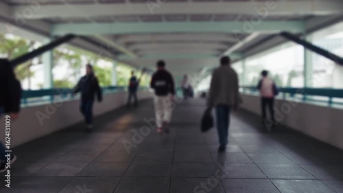 Close-up view of pedestrians walking on a modern pedestrian bridge in Hong Kong. The scene showcases blurred figures creating a dynamic urban atmosphere in a busy city setting