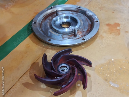 Schilderij op canvas Close-up of a disassembled pump impeller and metal casing on a workshop floor