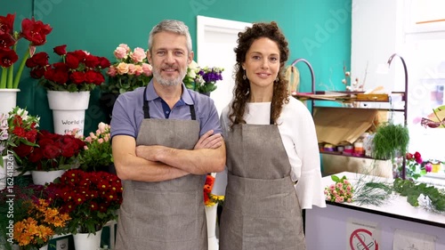 Professional florist standing confidently with crossed arms inside compact flower shop, embodying small business ownership and expertise