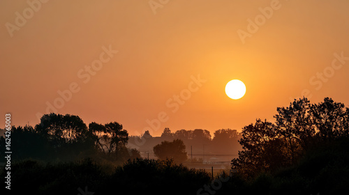 Vibrant orange sunset sky with low sun over distant horizon landscape