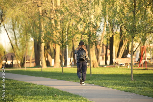 Wallpaper Mural A young girl in a sports uniform walks alone along a park alley. A walk in the fresh air among summer greenery. Fashion of modern youth. Torontodigital.ca